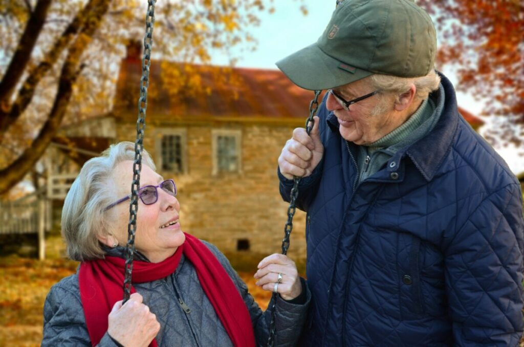An elderly couple sitting on a swing, reflecting the theme of Who will care for you in old age if you don’t have kids? through companionship and independence.