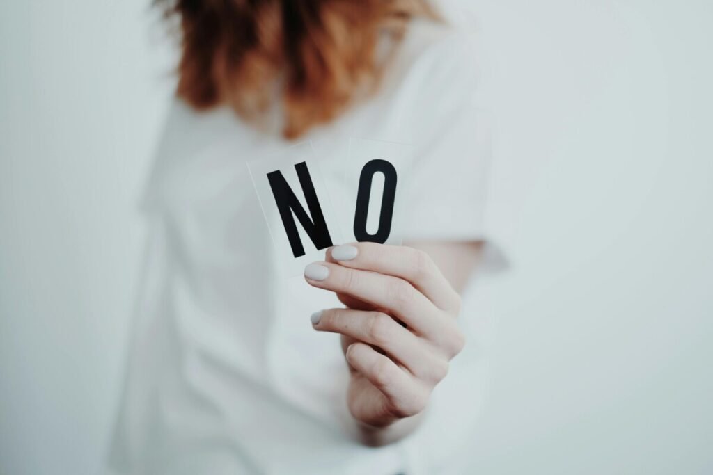 Close-up of hands holding wooden block letters spelling "NO," symbolizing the choice to reject procreation and addressing the question: What Is Antinatalism — and Is It the Same as Being Childfree?