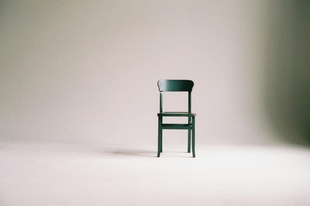Minimalist living concept — simple wooden chair against white wall representing The Childfree Minimalist: 5 Ways Less Clutter Equals More Freedom.