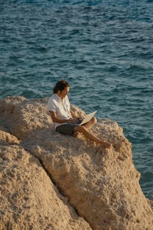 A man working on a laptop while sitting on a mountain peak—illustrating the career flexibility and autonomy that are among the 10 best hobbies for childfree adults.