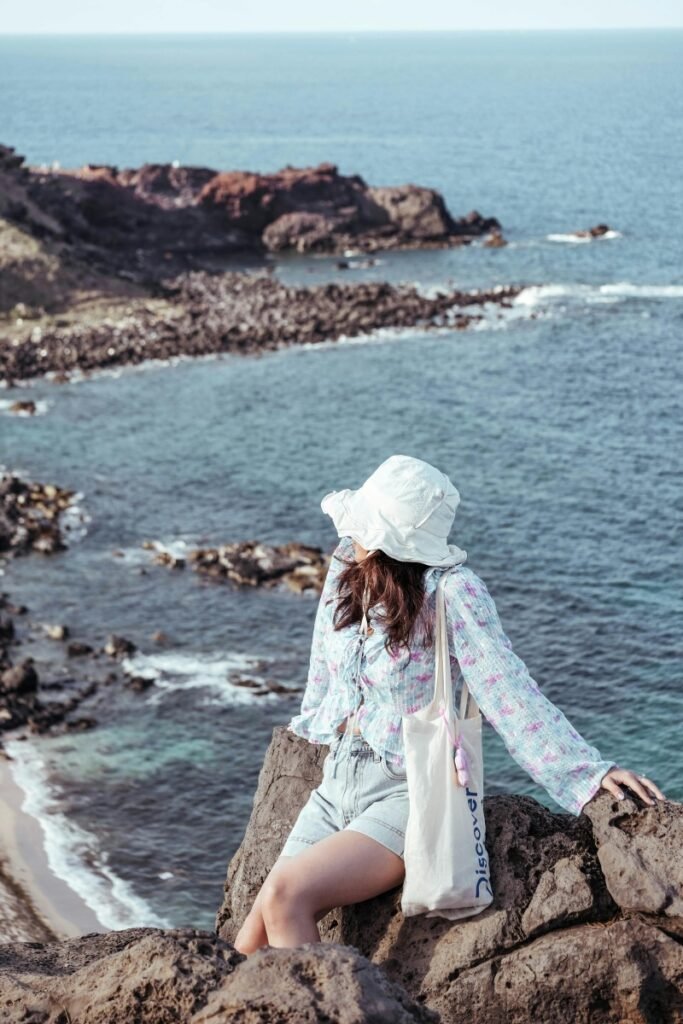 A woman standing on a scenic cliffside overlooking the ocean during the quiet months of the childfree travel season.