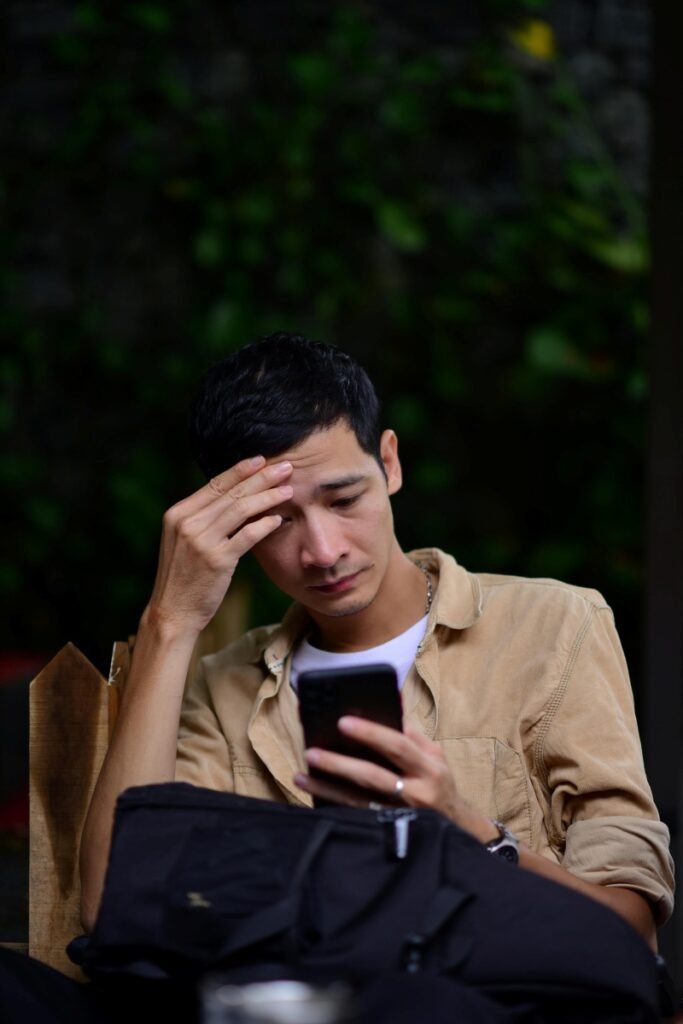 Stressed man checking dating app messages due to unclear childfree dating profile.